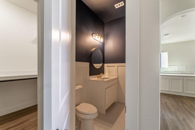 bathroom with visible vents, toilet, a wainscoted wall, wood finished floors, and vanity