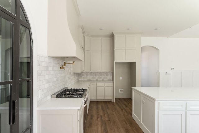 kitchen with tasteful backsplash, dark wood-style floors, custom exhaust hood, black fridge, and gas stove