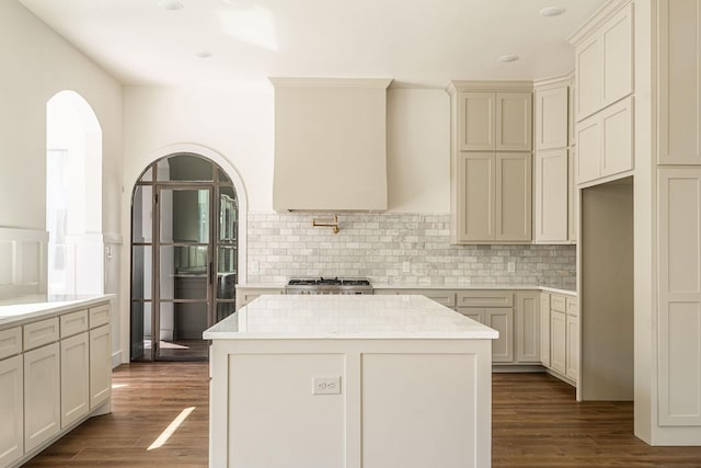 kitchen featuring a kitchen island, arched walkways, decorative backsplash, and dark wood-type flooring