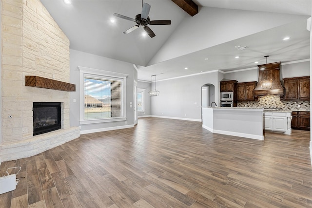 unfurnished living room with dark wood-style floors, arched walkways, a fireplace, ceiling fan, and high vaulted ceiling