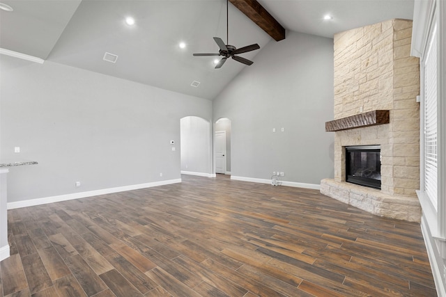 unfurnished living room featuring visible vents, arched walkways, wood finished floors, a fireplace, and beam ceiling