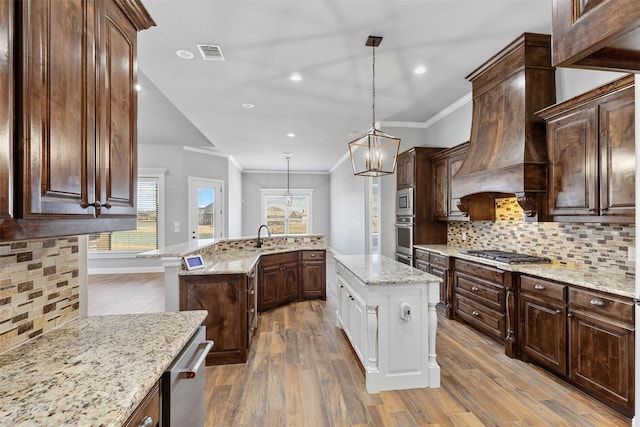 kitchen with an island with sink, appliances with stainless steel finishes, visible vents, and wood finished floors