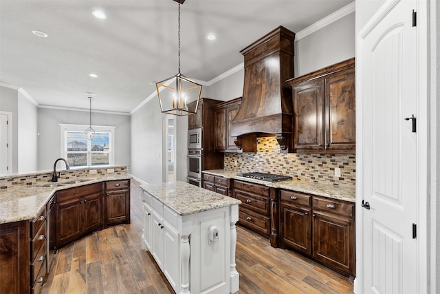 kitchen featuring a kitchen island, a sink, appliances with stainless steel finishes, tasteful backsplash, and custom range hood