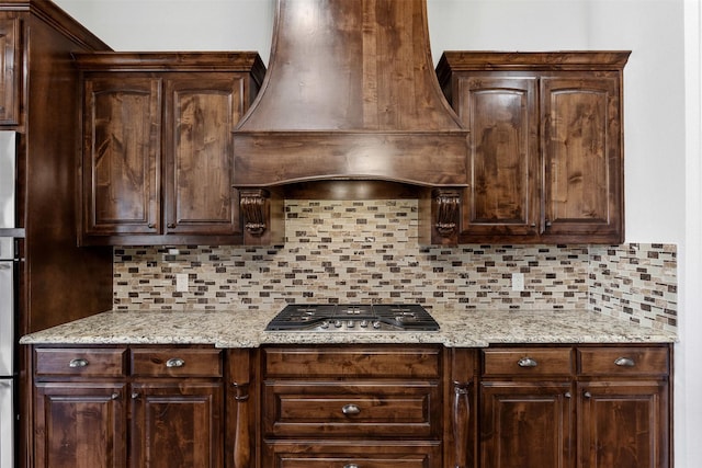 kitchen featuring premium range hood, stainless steel gas cooktop, and dark brown cabinets