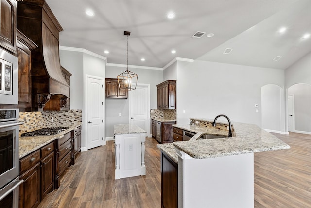 kitchen featuring a center island with sink, arched walkways, visible vents, stainless steel appliances, and a sink