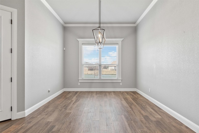 unfurnished dining area featuring an inviting chandelier, baseboards, ornamental molding, and wood finished floors