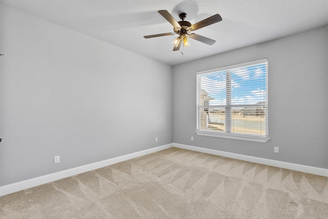 spare room featuring light carpet, ceiling fan, and baseboards