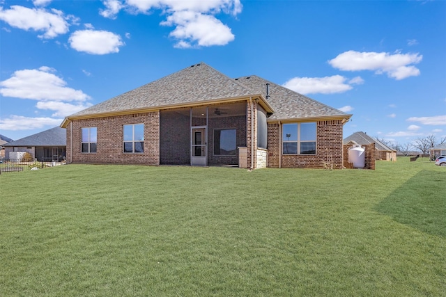 back of property with a yard, a shingled roof, and brick siding