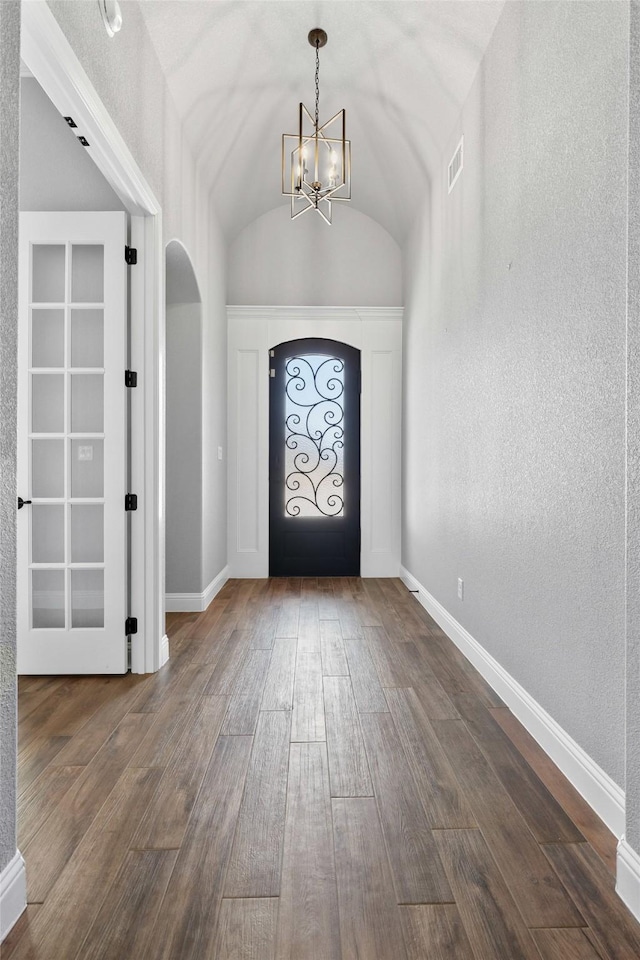 foyer entrance with arched walkways, dark wood-style flooring, lofted ceiling, and baseboards