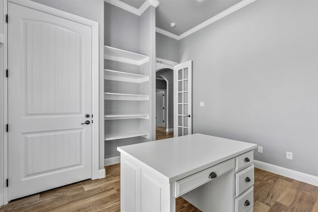 spacious closet with light wood-type flooring and arched walkways