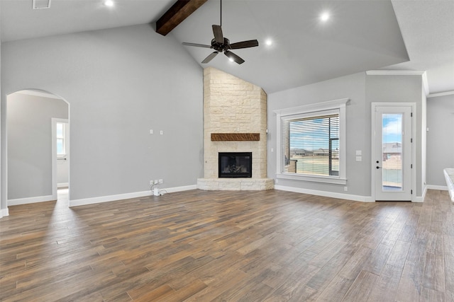 unfurnished living room featuring arched walkways, beam ceiling, dark wood-type flooring, a ceiling fan, and high vaulted ceiling