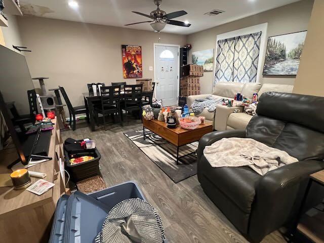 living room with visible vents, a ceiling fan, and wood finished floors