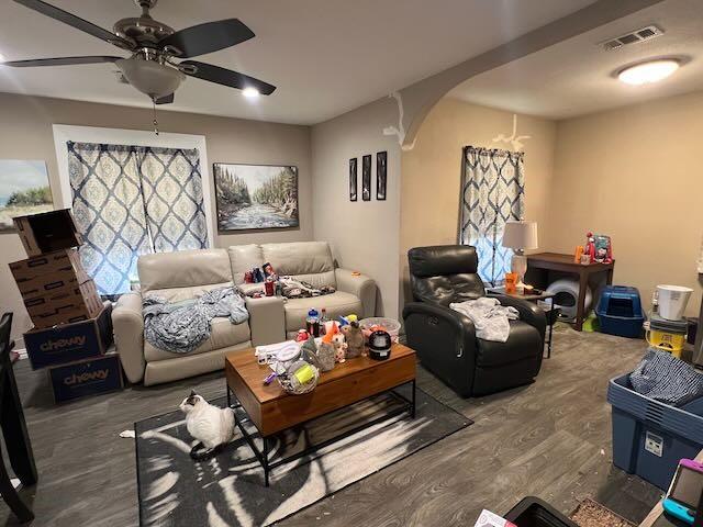 living area with arched walkways, ceiling fan, wood finished floors, and visible vents