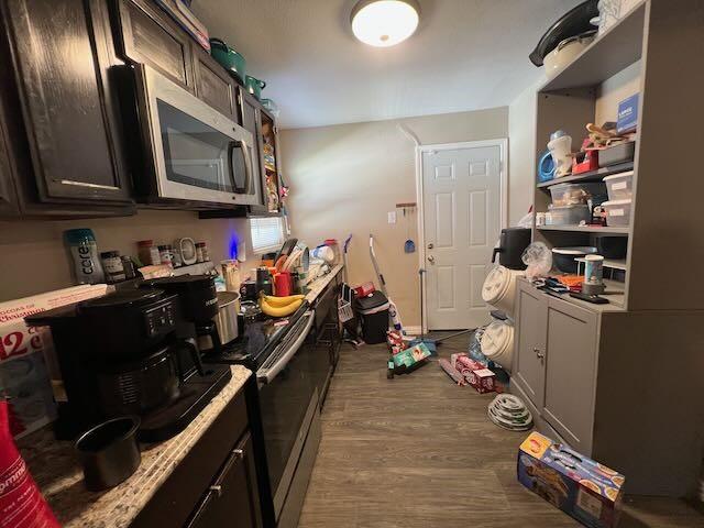 kitchen with light countertops, stainless steel microwave, electric range, and wood finished floors