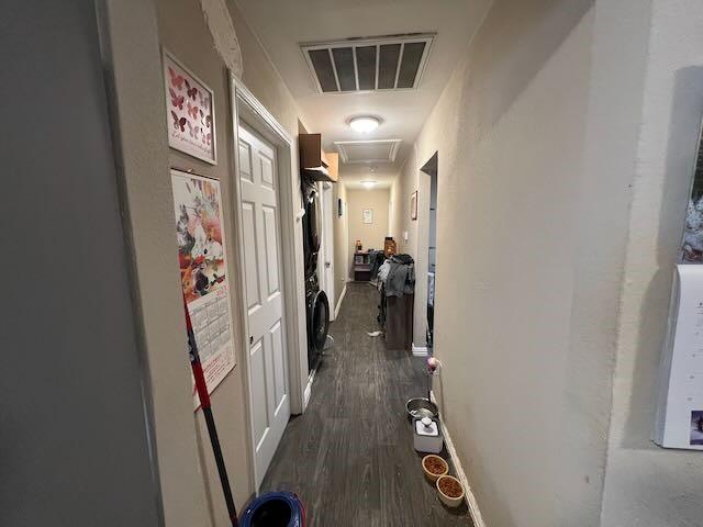 corridor featuring attic access, baseboards, visible vents, and dark wood-type flooring