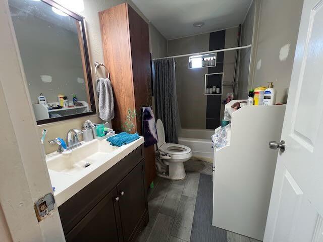 bathroom featuring toilet, shower / bath combo, wood finished floors, and vanity