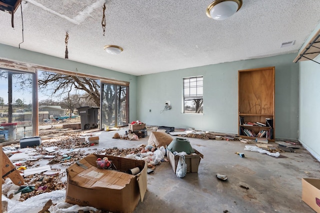 miscellaneous room with unfinished concrete floors, visible vents, and a textured ceiling