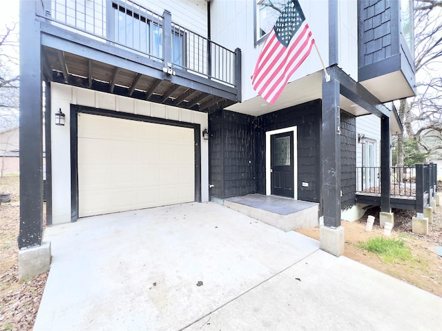 entrance to property featuring driveway, a balcony, and an attached garage