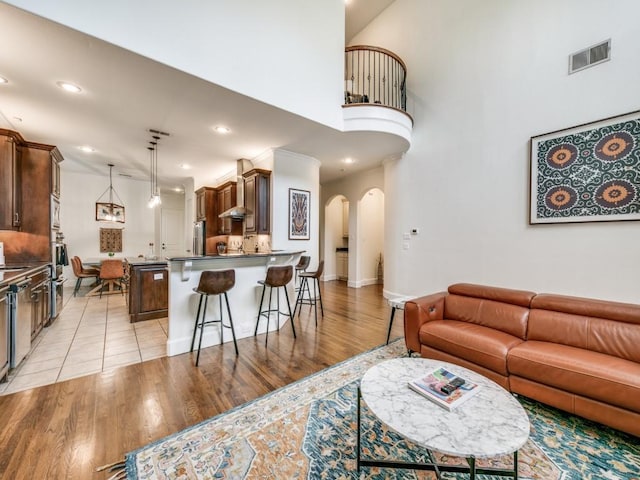 living room featuring visible vents, arched walkways, baseboards, light wood-style flooring, and recessed lighting