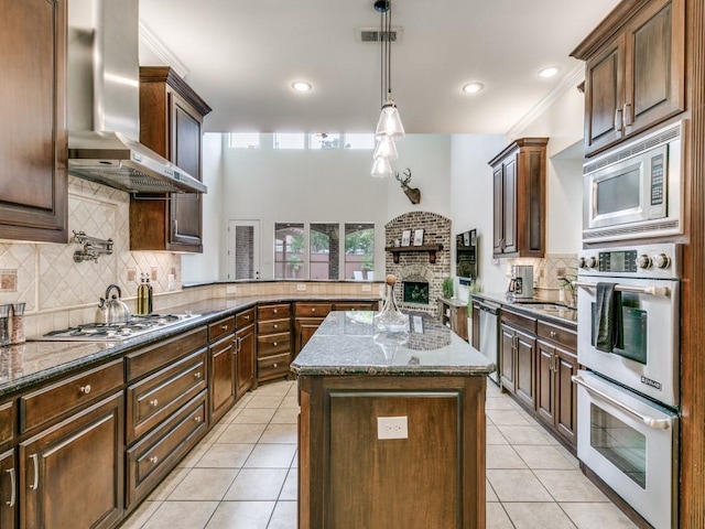 kitchen with visible vents, wall chimney exhaust hood, appliances with stainless steel finishes, dark stone countertops, and light tile patterned flooring