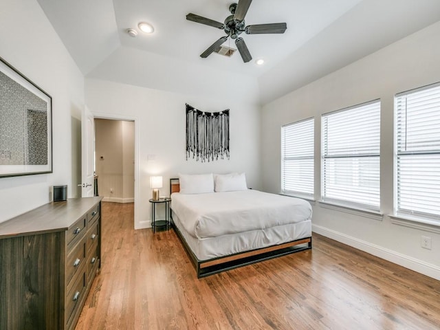 bedroom with recessed lighting, wood finished floors, baseboards, vaulted ceiling, and a raised ceiling