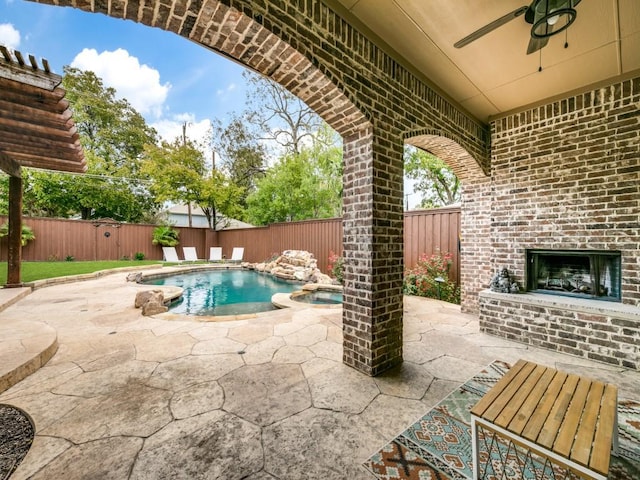 view of swimming pool with a pool with connected hot tub, a patio area, a fenced backyard, and a ceiling fan