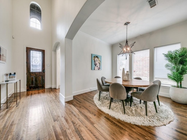 dining room featuring arched walkways, wood finished floors, a wealth of natural light, and a chandelier