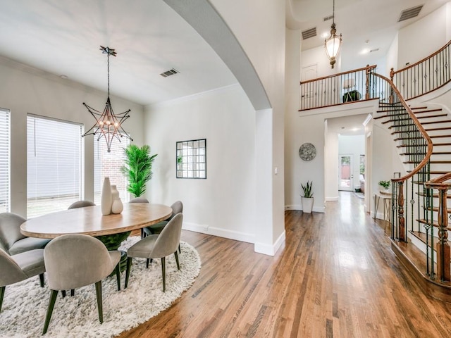 dining room featuring arched walkways, wood finished floors, visible vents, and baseboards