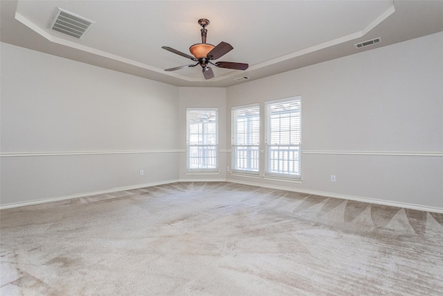 carpeted spare room featuring ceiling fan, baseboards, visible vents, and a raised ceiling