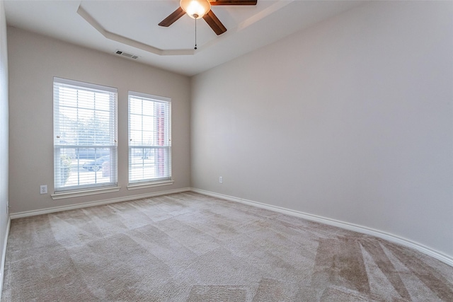 spare room with baseboards, visible vents, a raised ceiling, a ceiling fan, and carpet floors