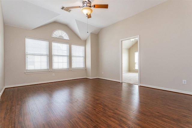 spare room with baseboards, visible vents, ceiling fan, dark wood-type flooring, and vaulted ceiling