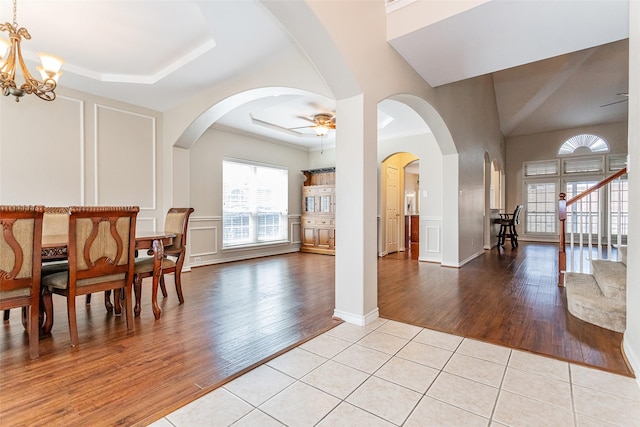 foyer with light tile patterned floors, a decorative wall, stairway, ornamental molding, and ceiling fan with notable chandelier