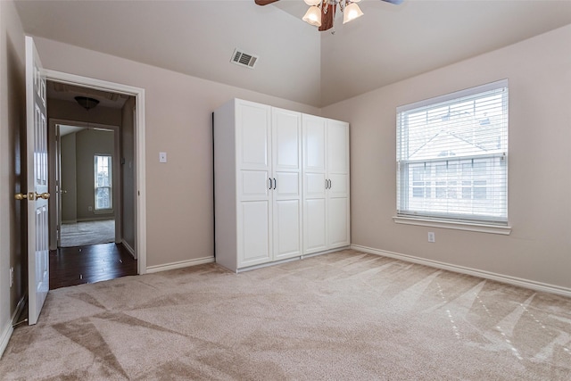 unfurnished bedroom with light carpet, visible vents, baseboards, vaulted ceiling, and a closet