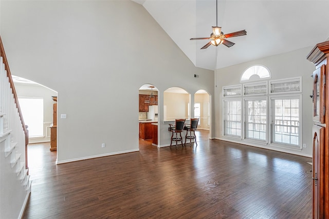 living room featuring ceiling fan, arched walkways, and dark wood-style flooring