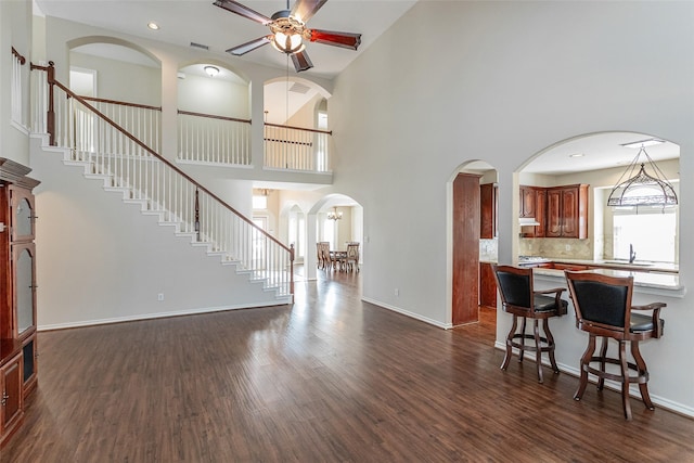 living area featuring recessed lighting, dark wood finished floors, baseboards, and stairs