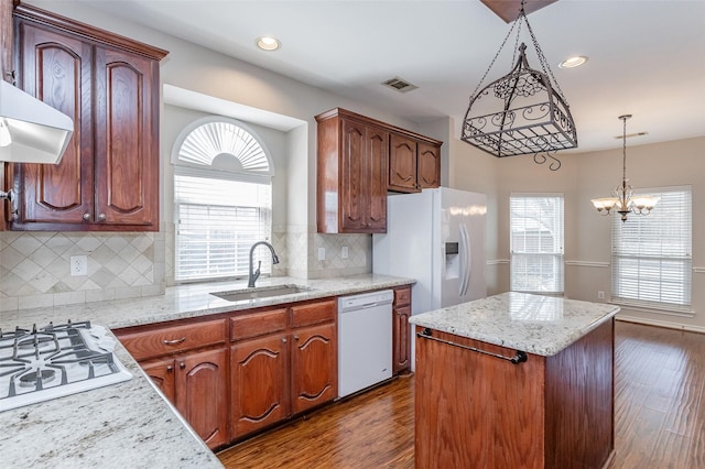 kitchen with white appliances, visible vents, a kitchen island, dark wood-style flooring, and a sink