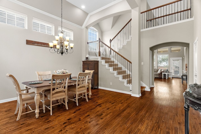 dining room featuring arched walkways, stairway, wood finished floors, and baseboards