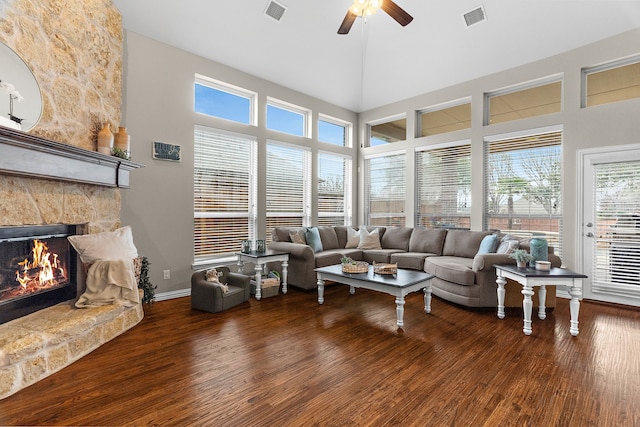 living room with visible vents, a stone fireplace, and wood finished floors