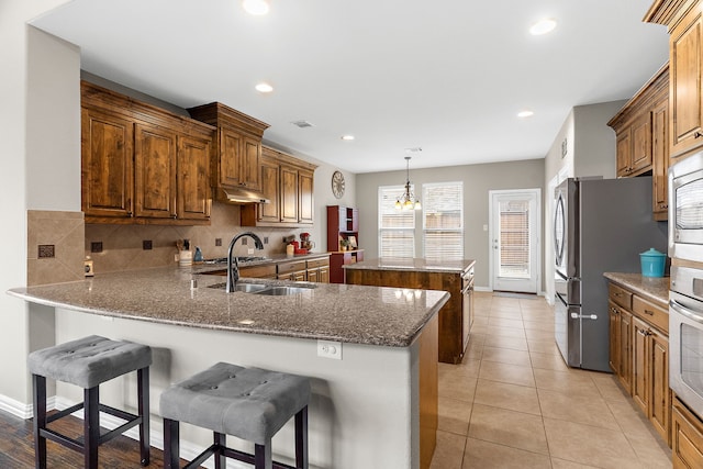 kitchen featuring decorative backsplash, a center island, a peninsula, stainless steel appliances, and a sink