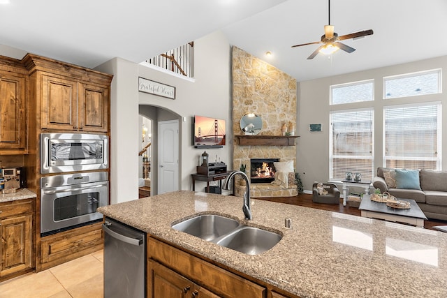 kitchen with open floor plan, stainless steel appliances, a fireplace, and a sink