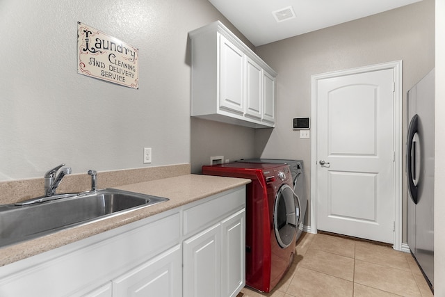 clothes washing area with cabinet space, visible vents, independent washer and dryer, a sink, and light tile patterned flooring