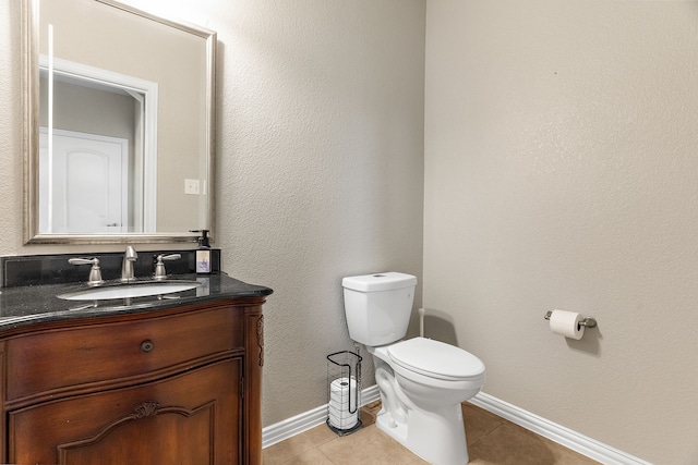 half bathroom with tile patterned flooring, baseboards, vanity, and toilet