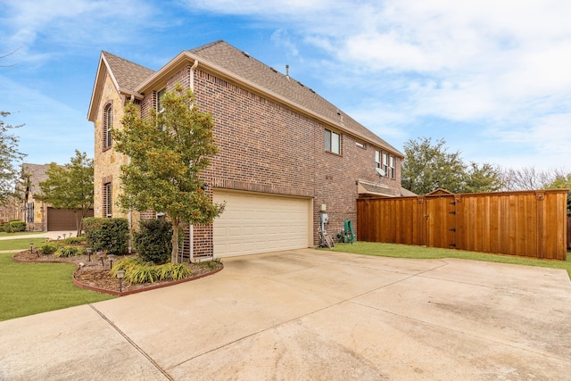 view of property exterior featuring a gate, brick siding, driveway, and a lawn