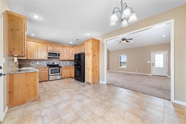 kitchen featuring stainless steel appliances, light colored carpet, backsplash, a sink, and light stone countertops