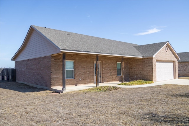 ranch-style house with a garage, brick siding, a shingled roof, and fence