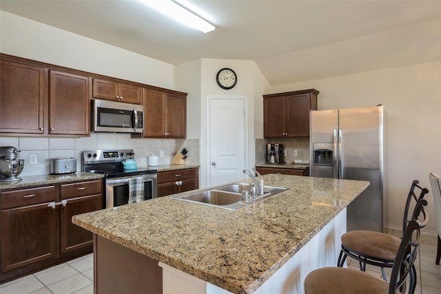 2278 Bryant Ln, Fate, TX 75189 - kitchen featuring stainless steel appliances, a sink, light tile patterned floors, tasteful backsplash, and a kitchen bar