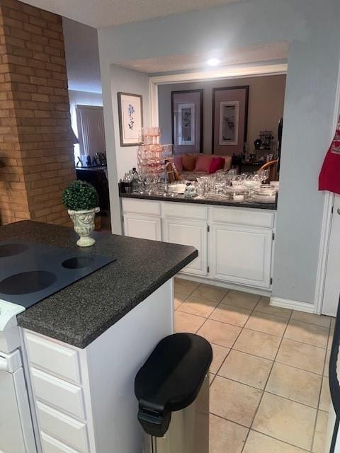 kitchen featuring light tile patterned floors, electric range, dark countertops, and white cabinets