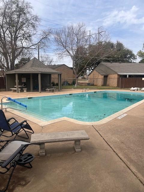 community pool featuring fence, an outbuilding, an exterior structure, and a patio