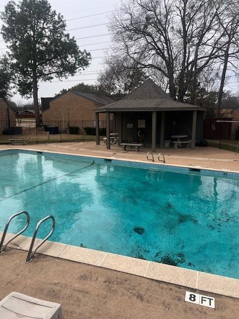 pool featuring a patio area, fence, an exterior structure, and an outbuilding