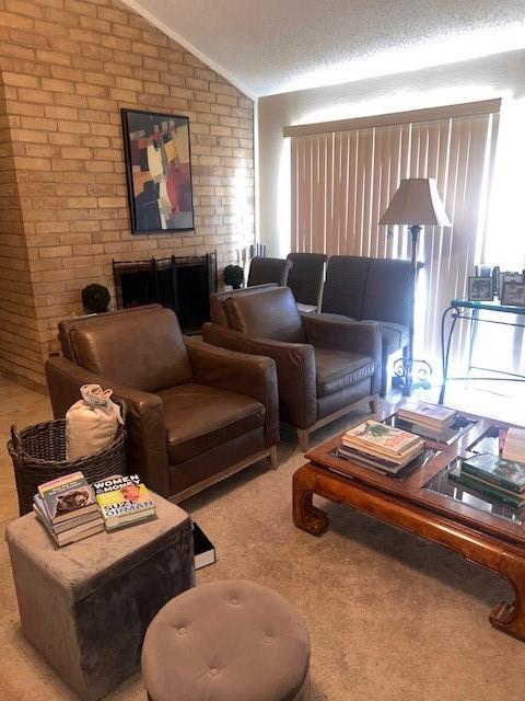 living room featuring lofted ceiling and brick wall